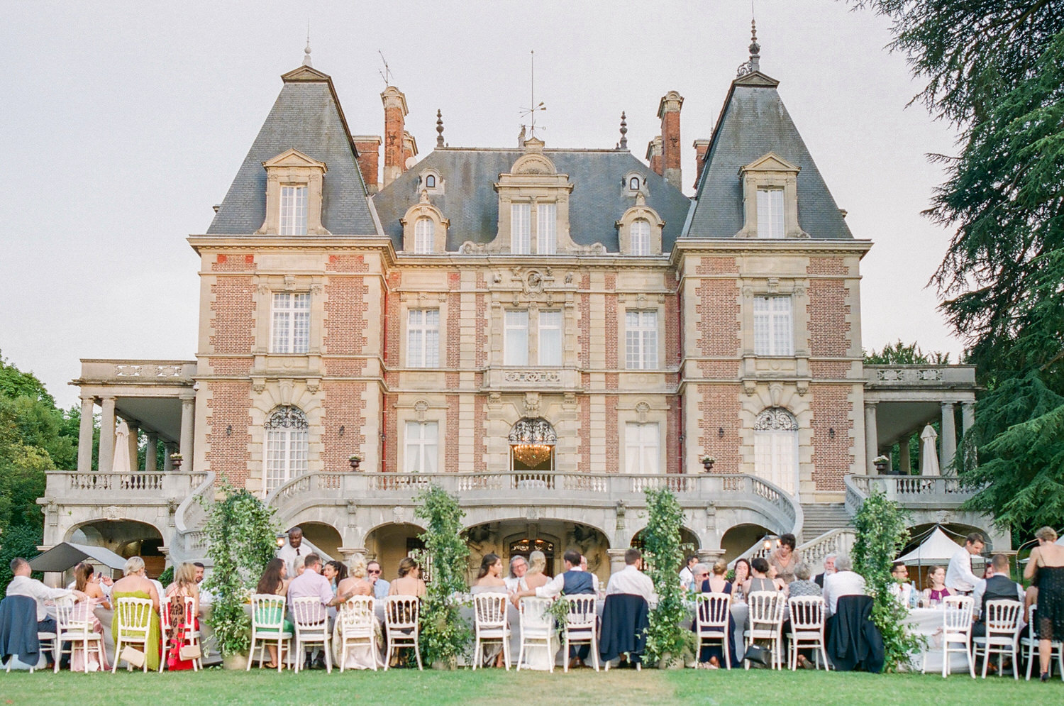 Outdoor wedding dinner at Château de Bouffémont in a garden setting.

