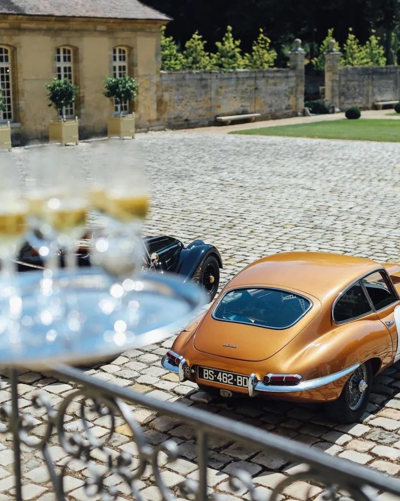 Château de Villette exuding charm with stylish cars and champagne glasses.